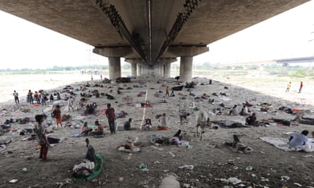 La gente descansa bajo un puente para evitar el calor abrasador en Delhi, India