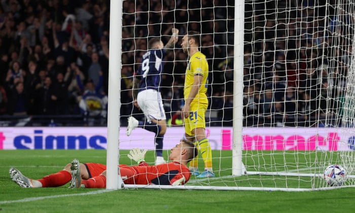 Ukraine’s goalkeeper Anatolii Trubin and Oleksandr Karavaev look dejected as Scotland’s Lyndon Dykes celebrates scoring their second goal.