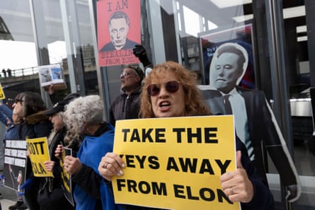 Demonstrators with the activist group Rise & Resist stand outside the Tesla Showroom in Manhattan’s Meatpacking District holding signs that read ‘TAKE THE KEYS AWAY FROM ELON’ ‘I AM STEALING FROM YOU.’ with an image of Musk and a life-size cardboard cutout of Musk making a fascist salute
