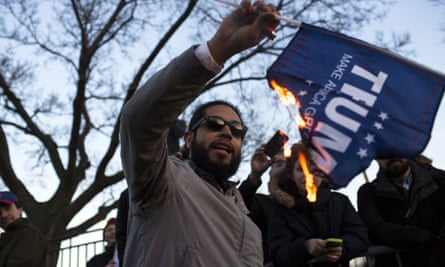 A protester burns a Trump campaign flag outside the venue.