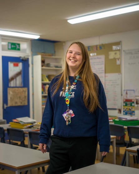 A smiling woman with long blond hair standing in a primary school classroom
