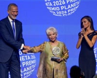 Isabel Allende smiles as she holds the Premio Planeta trophy while King Felipe VI shakes her by the hand and Queen Letizia looks on, applauding