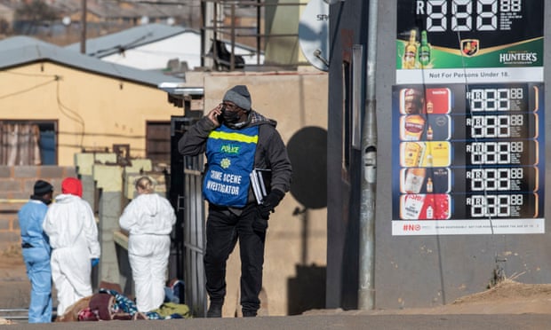 A police investigator and forensic personnel at the scene of the mass shooting at a Soweto bar in the early hours of Sunday