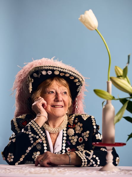 Wendy Loftus in her pearly outfit sat at a table next to a flower in a vase