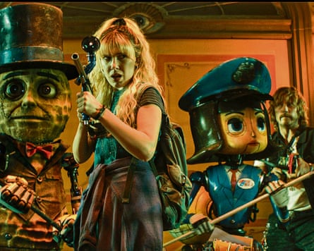 Two strange looking life sized caricatures holding weapons stand in a defensive pose with a woman and a man