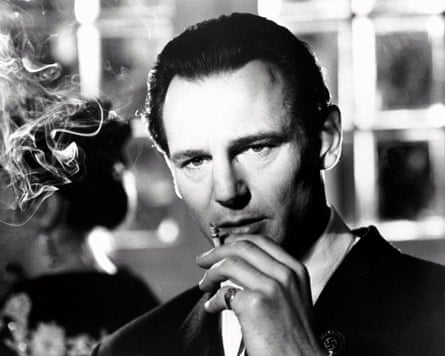 A black-and-white photo of Liam Neeson in Schindler’s List, smoking a cigarette