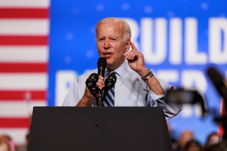 Joe Biden se tient sur un podium sur fond d'une bannière rouge, blanche et bleue avec un logo