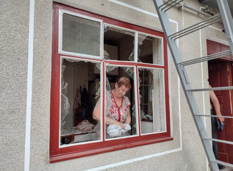 Una persona quita fragmentos de vidrio de una ventana después de un ataque con misiles rusos en Mykolaiv