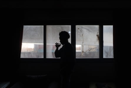 Silhouette of Nadir drinking a cup of something at his window.