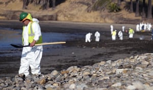 A clean up worker heads to the shoreline while a larger group of workers begin clean up operations at Refugio State Beachon 20 May.
