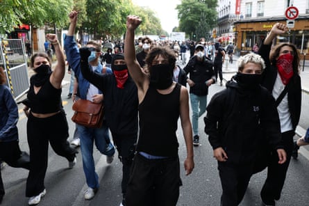 Masked protesters raise their fists as they march through the streets