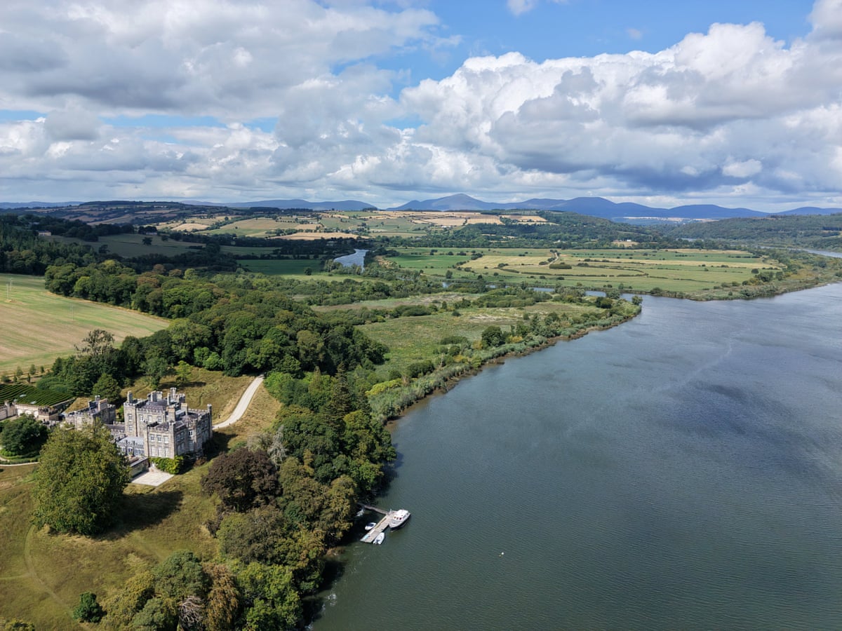 A distant view of Strancally Castle with the river and hills behind