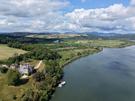 A distant view of Strancally Castle with the river and hills behind