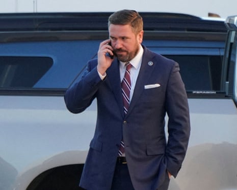 a man in a suit speaks on a phone outside