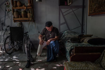 Oleksandr Petrov at his parent’s place in Voznesensk. His prosthetic leg is on the floor beside him and there is a wheelchair nearby.