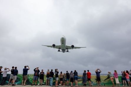 People watch a plane land on Rarotonga island