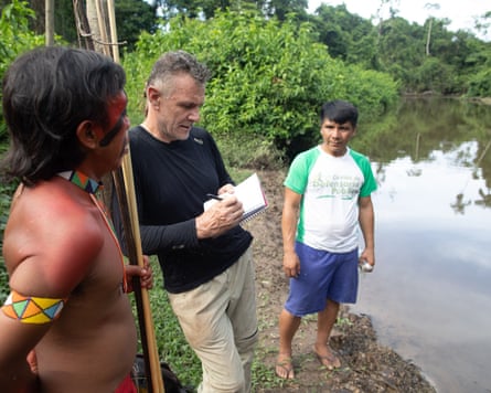 Dom Phillips interviewing two Indigenous men next to a river