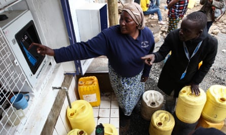 A woman is shown how to fetch water from one of the ATM-style water dispensers in the Mathare slums in Nairobi, Kenya.