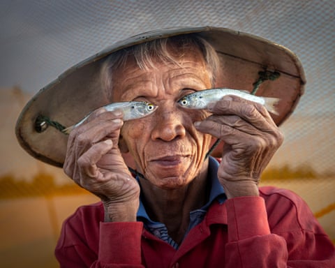 Humorous image of a fisher holding two small fish in front of his eyes
