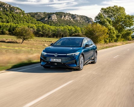 A black VW ID. 7 being driven along a country road with a mountain in the distance