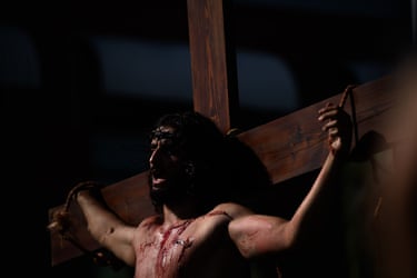 Image 8: A man covered in fake blood portraying Jesus Christ on a cross