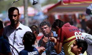 People cool off under an open-air shower in Baghdad as temperatures soar