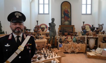 man in uniform stands in front of antiquities on display
