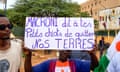 A supporter of the Nigerien military junta displays a sign that reads: 'Macron, tell your puppies to leave our land.’
