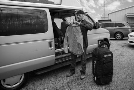 A man puts a garment connected a hanger successful beforehand of a ample van