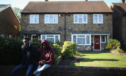 A group of young asylum seekers from Sudan sit on a wall outside their temporary housing in Longford, England
