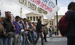 A protester holds a banner while others chant anti austerity slogans in front of the Athens Academy on Friday, May 6, 2016. Services have ground to a halt in Greece as workers start a three-day general strike protesting new bailout austerity measures they say will further decimate incomes, in a sign of growing discontent with the left-led coalition government.(AP Photo/Petros Giannakouris)