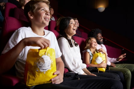 family group laughing in the light of a cinema screen