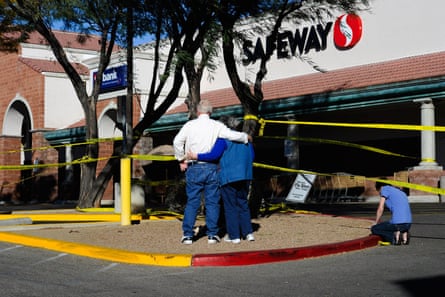 people stand near yellow crime scene tape outside a supermarket