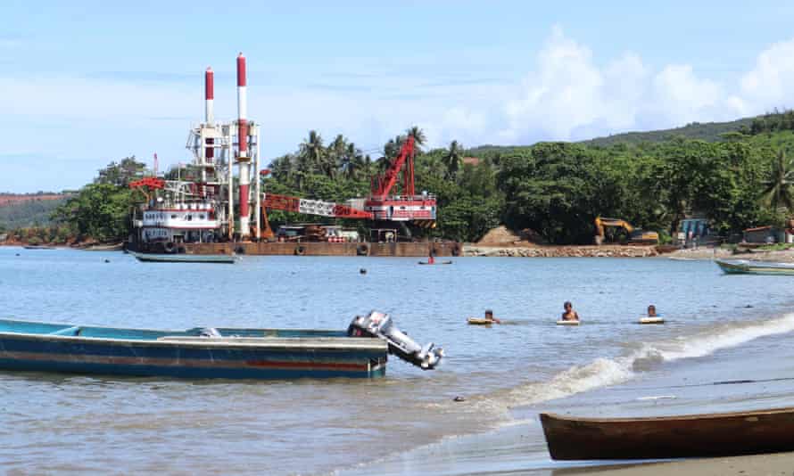 Children play on Kawasi beach as building work for a mining company port takes place along the shore.