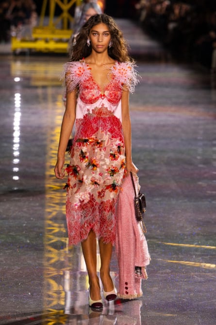 Model wears red and pink dress with feathered shoulders.