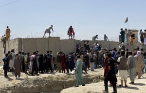 People struggle to cross the boundary wall of the airport as they try to flee the country
