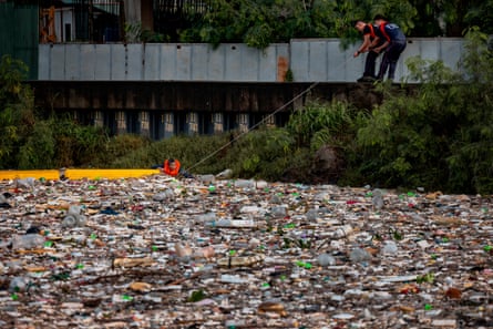 Workers attempt to clear a waterway full of plastic in Manila.