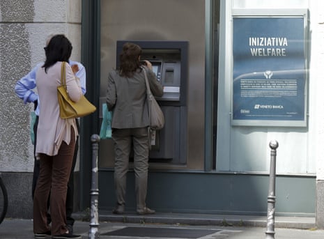 People line up at a cash machine of a Veneto Banca branch in Milan, Italy, Monday, June 26, 2017.