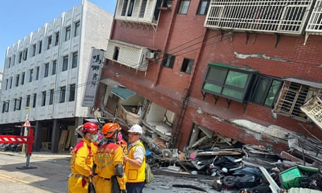 In this photo released by the Taiwan's National Fire Agency, members of a search and rescue team prepare outside a leaning building in the aftermath of an earthquake in Hualien, eastern Taiwan