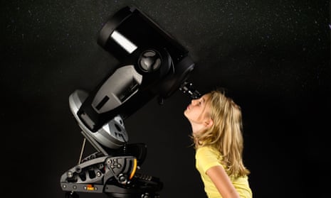 Young girl looking through a telescope