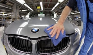 A worker cleans the hood of a BMW 3-series