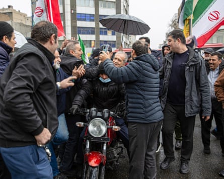 The Iranian president, Masoud Pezeshkian on the back of a motorbike is mobbed by supporters