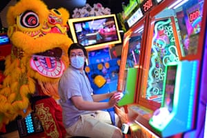 A man is interrupted by lion dancers as he plays arcade games in Sydney, Australia