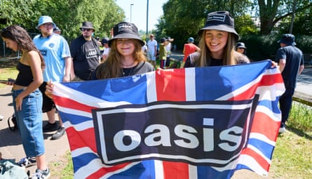 Lola Toft, left, and Neve Leckie-Traynor hold a union flag with the oasis logo written on it