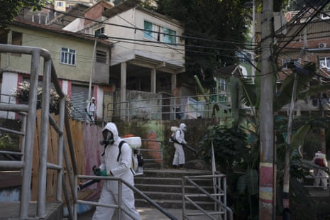 Volunteers spray disinfectant in an alleyway to help contain the spread of coronavirus in the Babilonia slum of Rio de Janeiro, Brazil, on Sunday, 12 July, 2020.