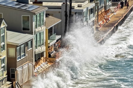 A wave crashing only meters across a seawall from homes.