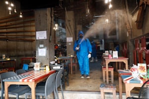 Health workers in protective suits spray disinfectant at a restaurant in Khao San during a clean-up operation after customers tested positive for coronavirus.