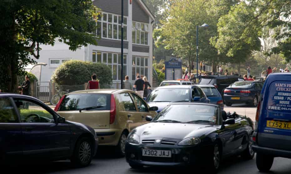 Cars queue to collect children outside a primary school in Aberystwyth, Wales