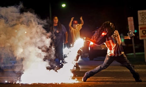 Protesters throw back a tear gas canister fired by police in Ferguson, Missouri, on 13 August 2014. 