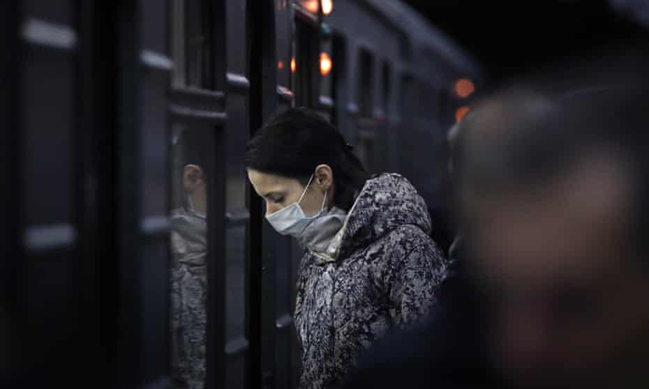 A woman in a face mask prepares to board a train